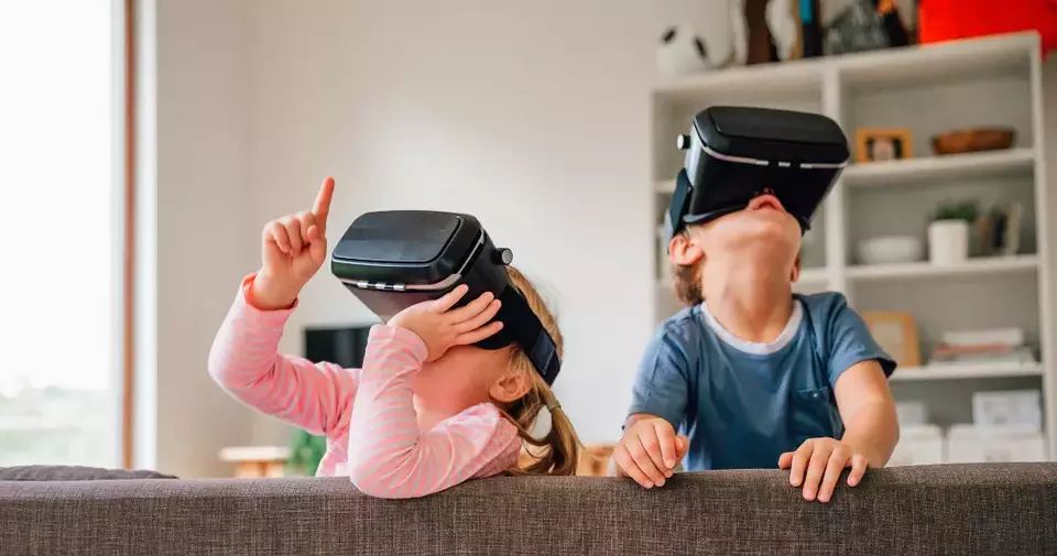 A little girl and a little boy wearing a VR Headset