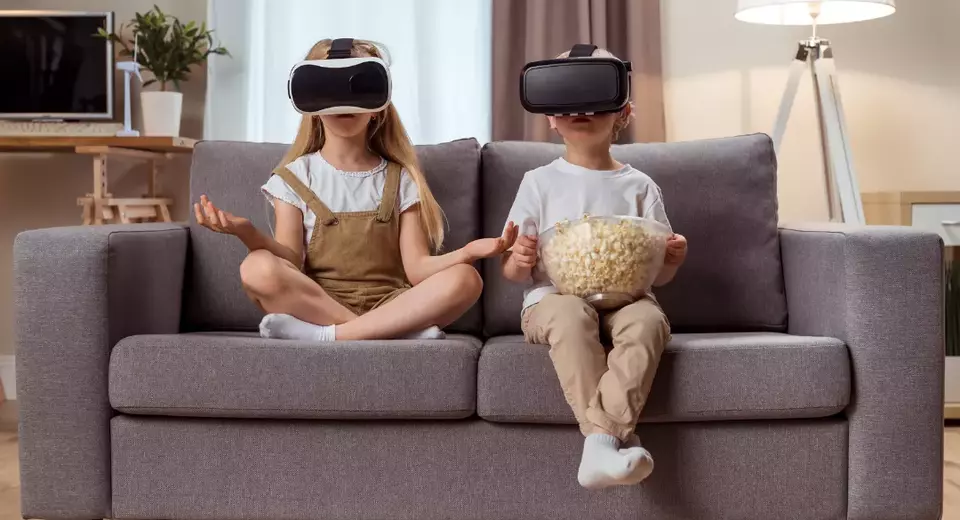A little girl and a little boy wearing VR headsets.