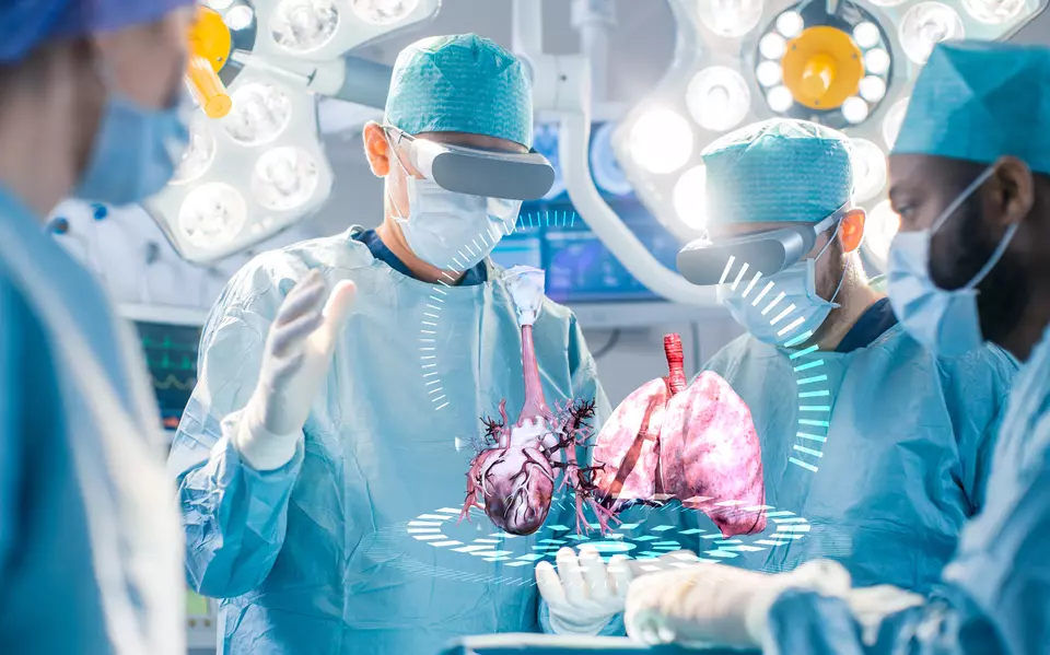 Surgeons wearing virtual reality headsets performing a simulated surgery with a 3D holographic projection of human heart and lungs