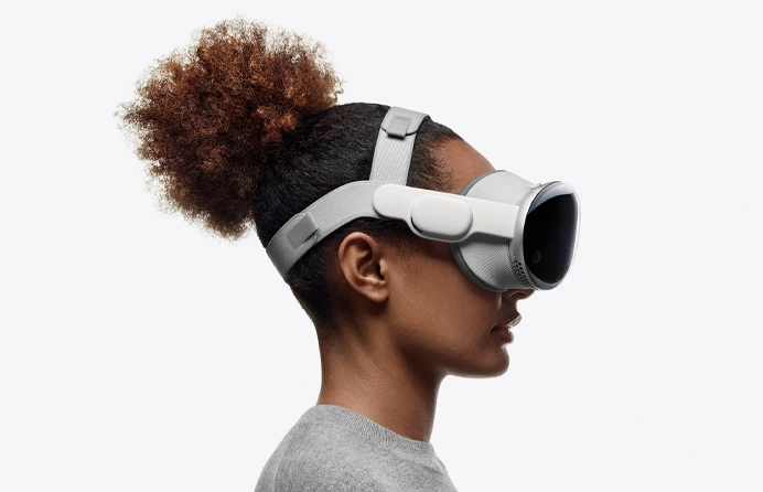 Profile view of a person with a high ponytail wearing Apple's Vision Pro VR headset.